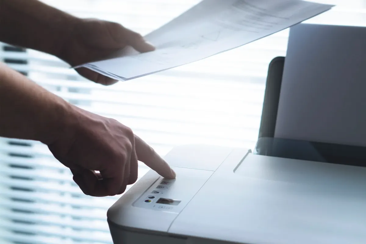 Manos con un documento junto a una impresora