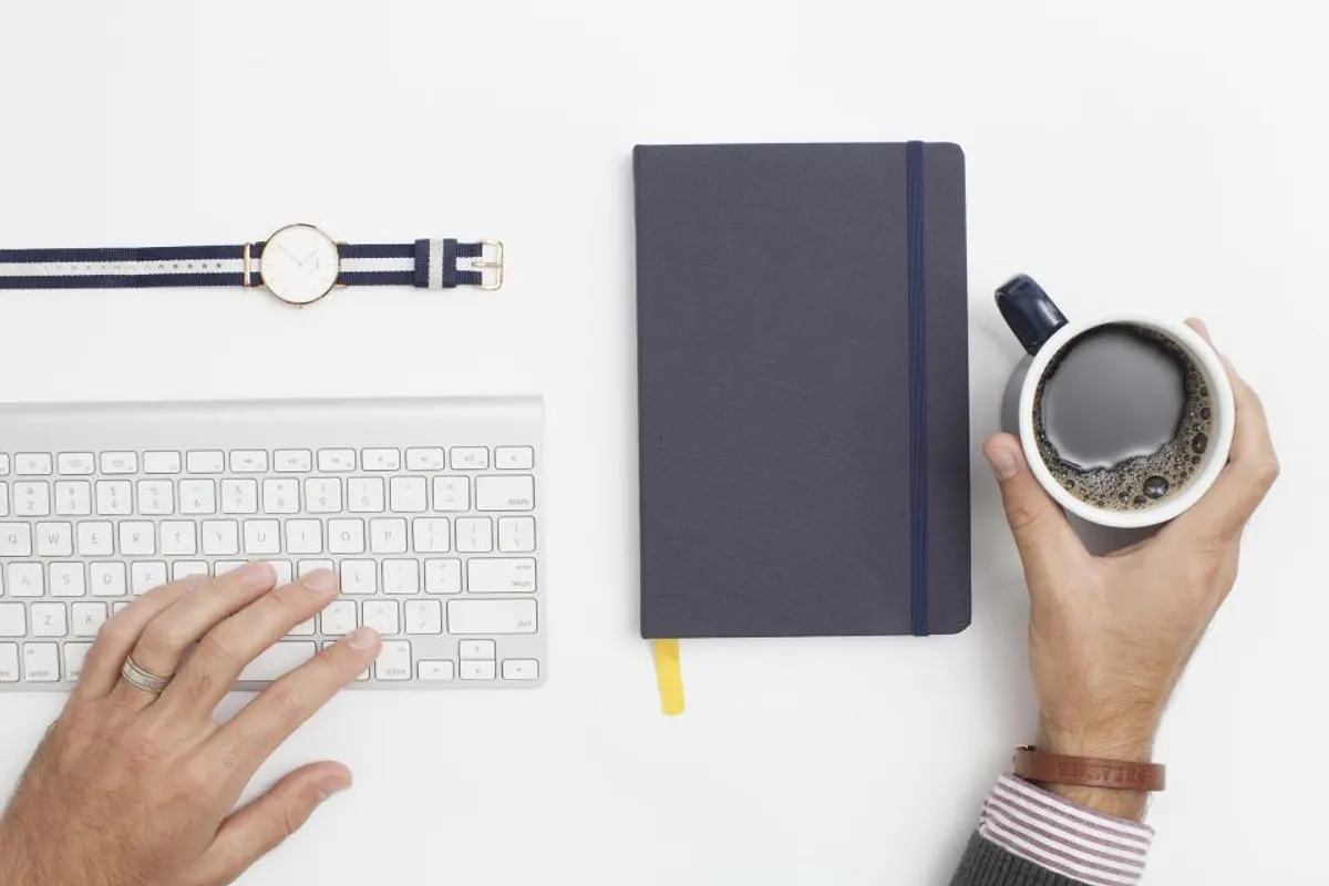 Teclado, cuaderno y taza de café en un escritorio