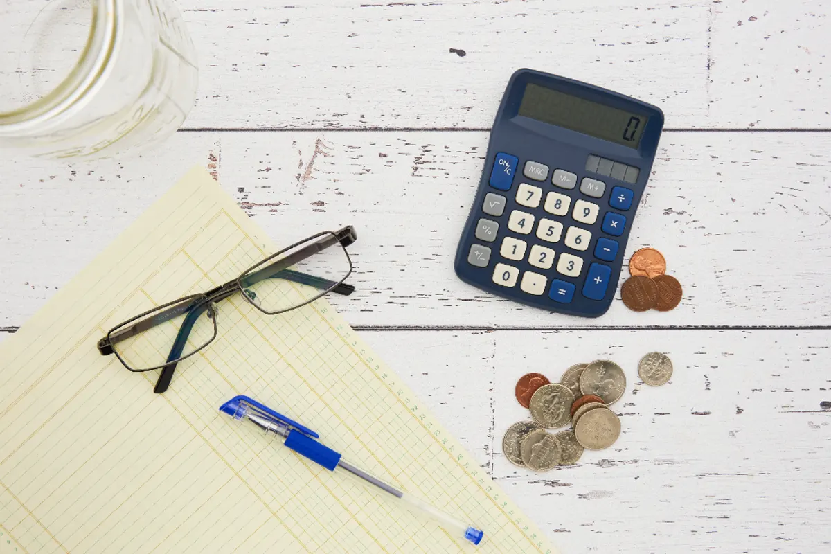 Calculadora, monedas y gafas sobre una mesa