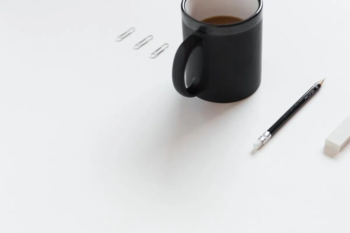 Taza y bolígrafo sobre un escritorio blanco